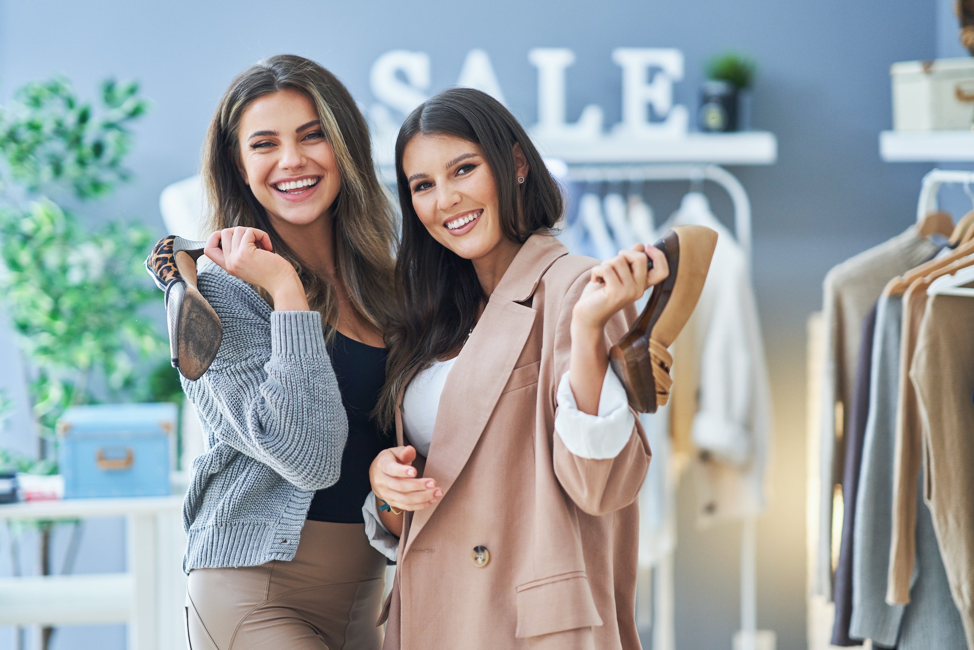 Two happy girls on shopping holding shoes